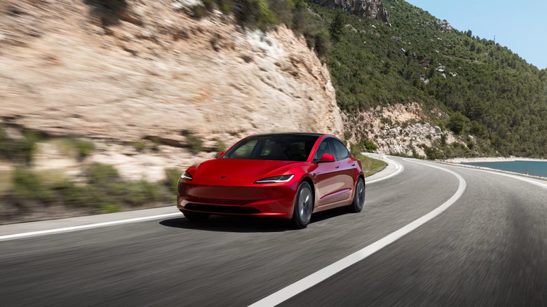 A red Tesla Model 3 Premium driving on the side of a hill