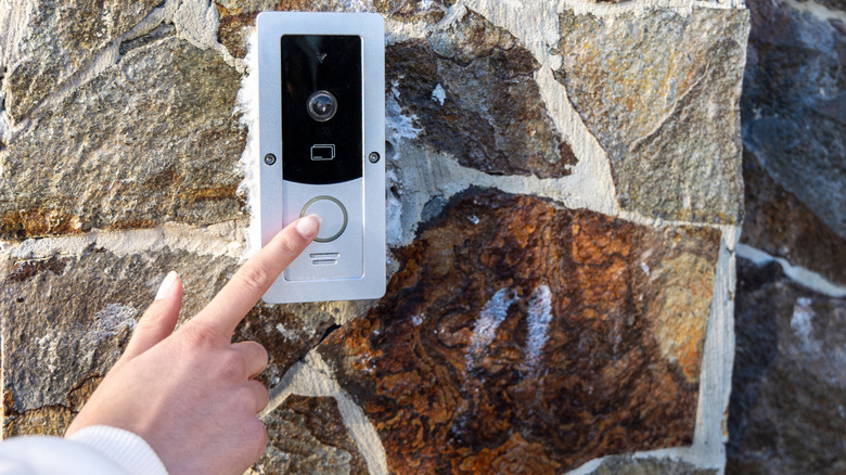 A person ringing the doorbell on a doorbell camera.
