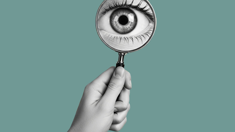 A graphic of a hand holding a magnifying glass over an eye.