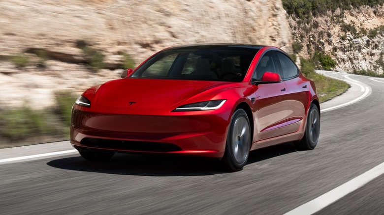 Red Tesla Model 3 Premium driving on a twisty cliffside road