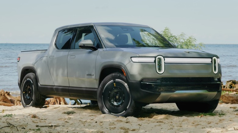 White Rivian R1T parked on a sandy beach