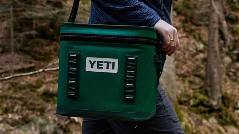 Person carrying a green Yeti Hopper Flip 12 cooler by their side