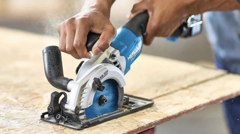 Close-up of a man using the Hercules compact circular saw to cut a board