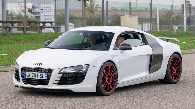 A white Audi R8 driving down a road.