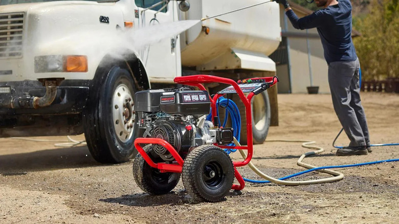 man using pressure washer on truck