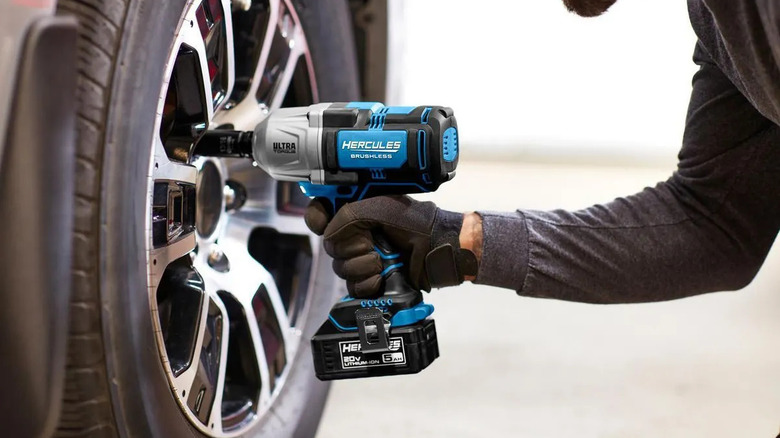 man using Hercules drill on car wheels