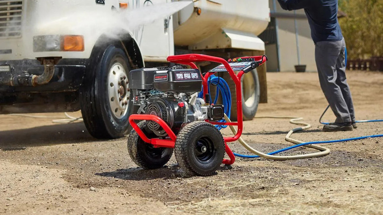 man using pressure washer on car