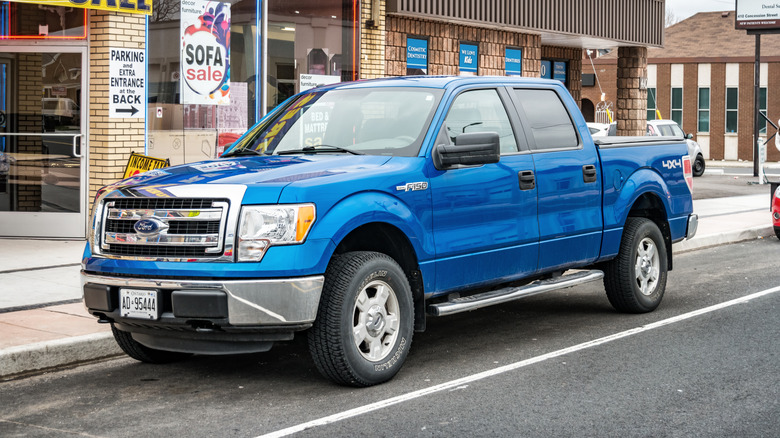 A blue 2012 Ford F-150 parked in an urban city environment.