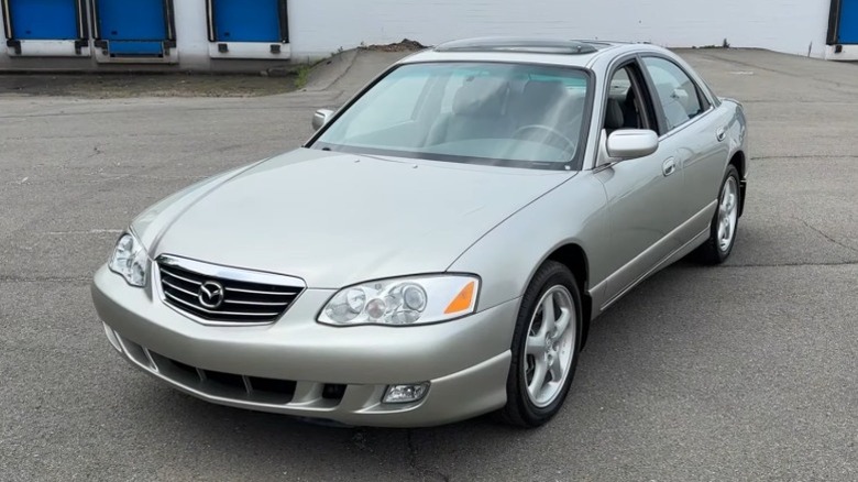 Silver Mazda Millenia in an empty lot with a building in the background