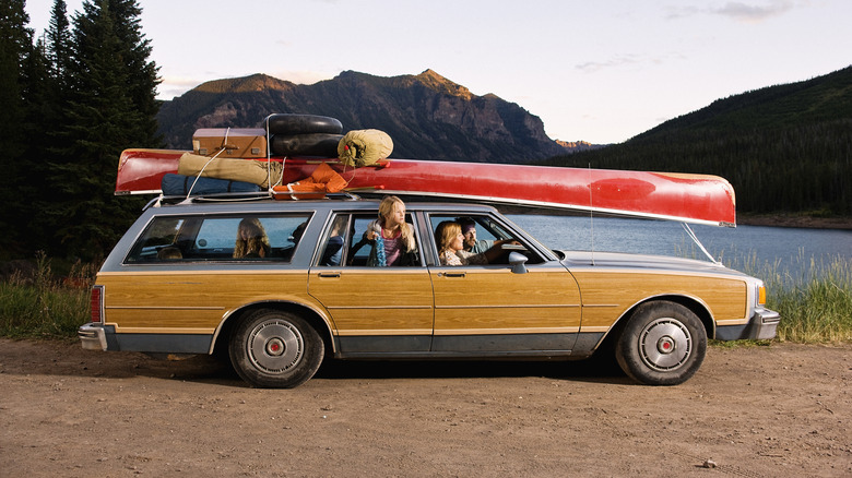A side profile view of an old family station wagon parked near a lake.