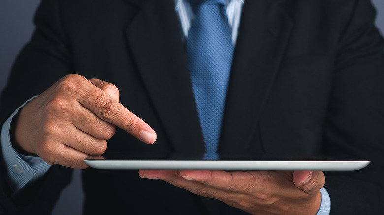 man pointing at held tablet