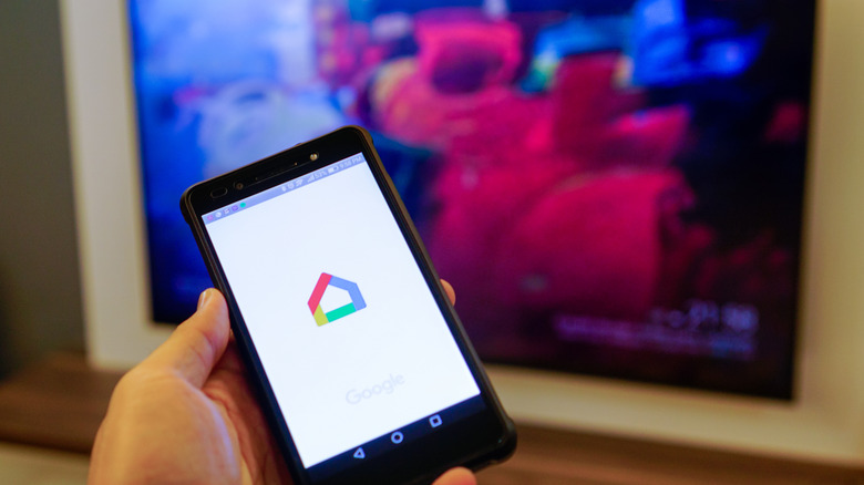hand holding phone with google home