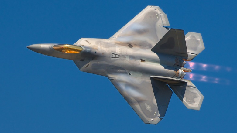 An F-22 Raptor flying with its vapor trail shooting out of its jet engines