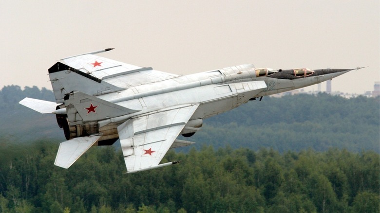 A Mikoyan-Gurevich MiG-25 Foxbat flying low over trees after takeoff