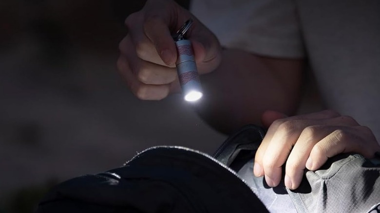 Person using Olight I1R 2 Pro to look in backpack