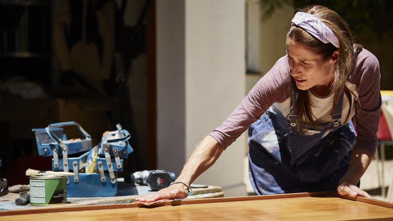 woman polishing wood outside