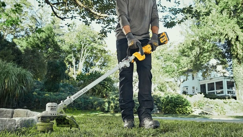 Person using folding DeWalt string trimmer