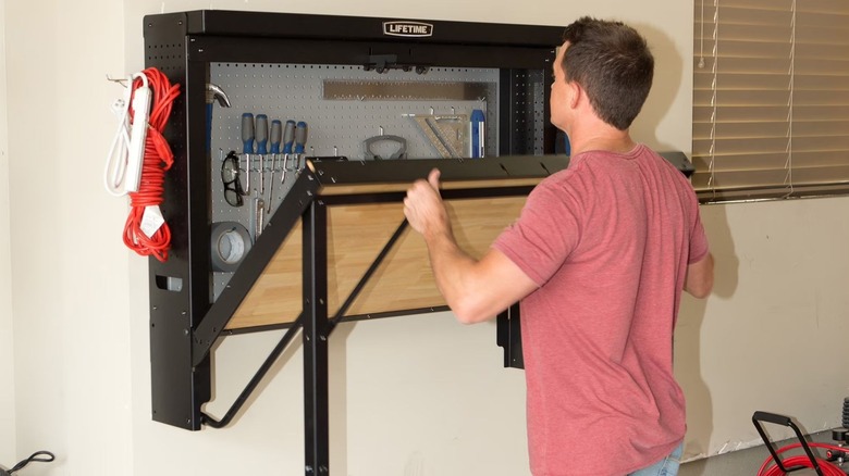 man folding up Lifetime Wall-Mounted Work Table