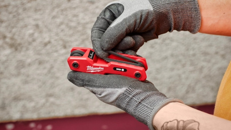 person wearing gloves, holding a Milwaukee SAE/Metric Folding Hex Key Set