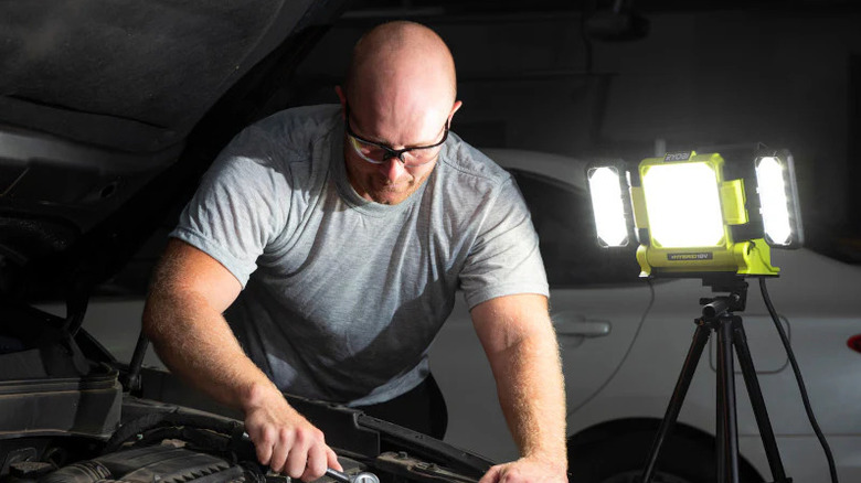 A man working on car with Ryobi LED panel installed