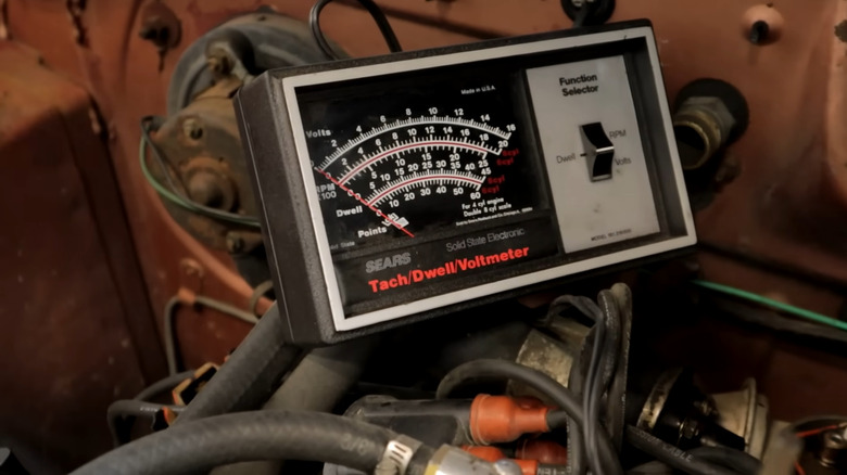 Combination dwell / voltmeter resting on vintage engine in engine bay