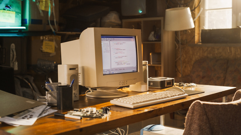old computer placed on a work desk with a chain in the front and a lamp in background