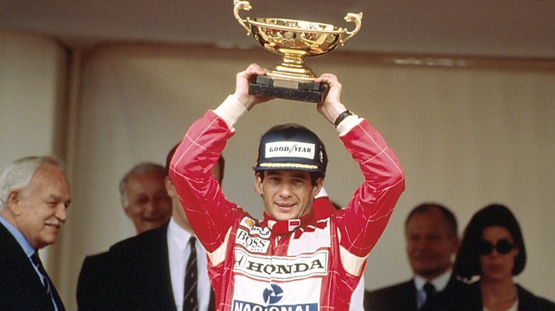 Ayrton Senna on the Monaco podium holding the winners trophy above his head