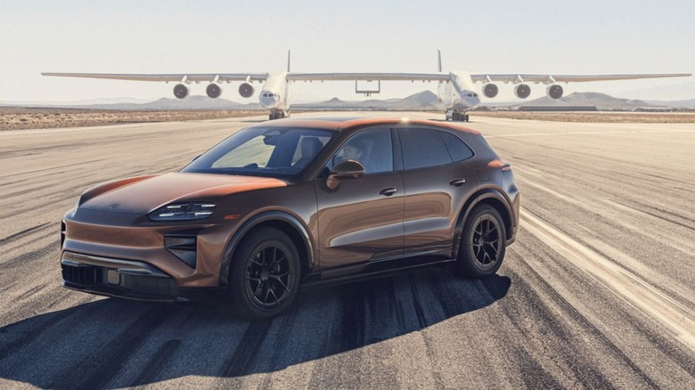 Front 3/4 view of golf Porsche Cayenne Turbo EV parked on airport runway.