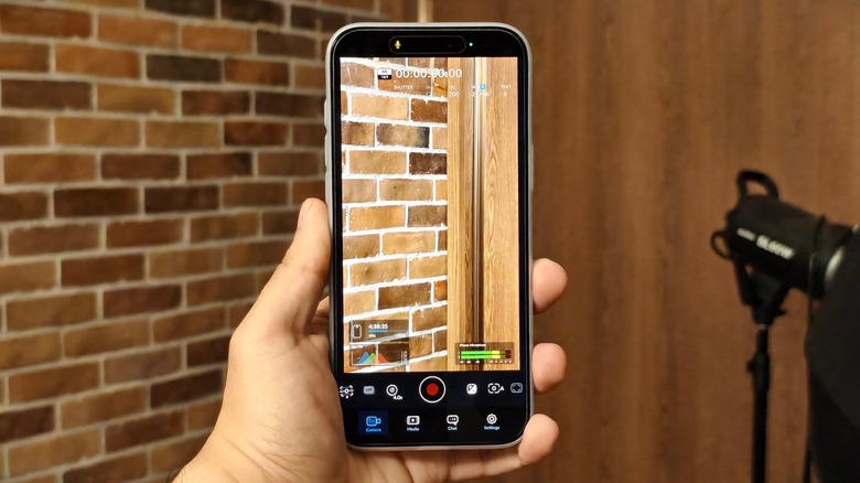 A person holding an iPhone 17 Pro Max with the Blackmagic Camera app open