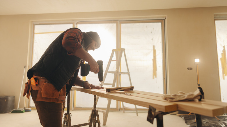 Man drilling wood in a living room