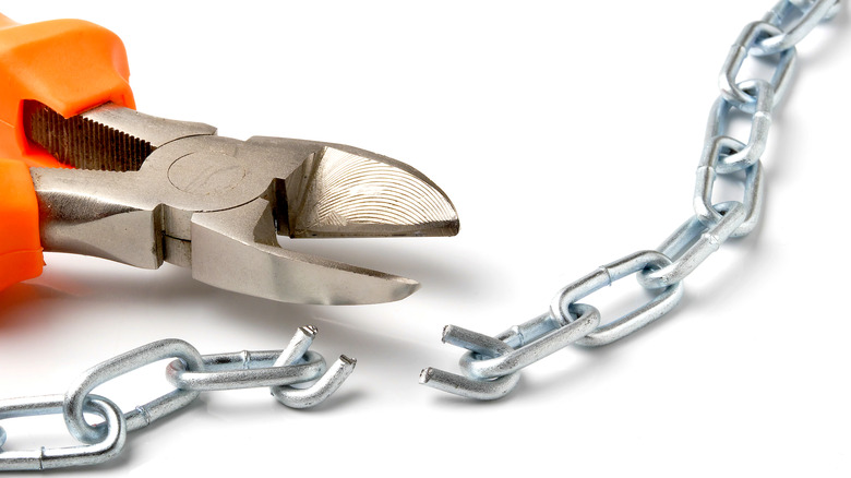 Close-up of pliers cutting a silver chain link