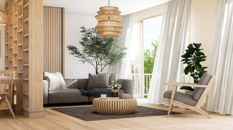 Neutral colored room with a chair, sofa, table, and chandelier