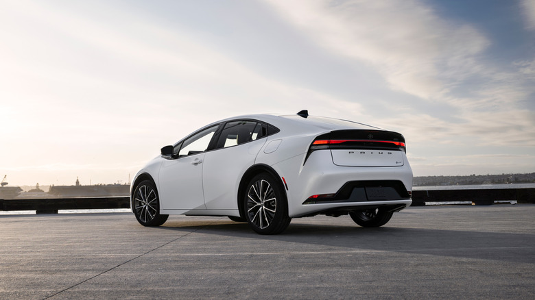 A white 2026 Toyota Prius sitting on tarmac with the rear Prius logo in view