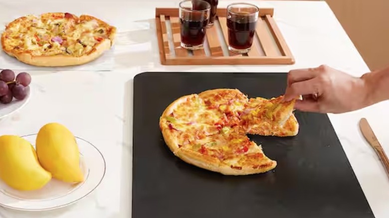 Person serving pizza off of SVOPES pizza stone