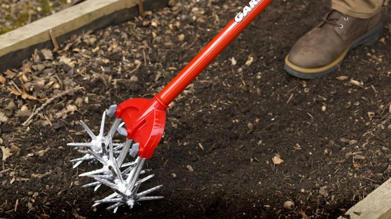 A gardener using Garden Weasel aerator on a raised planter bed