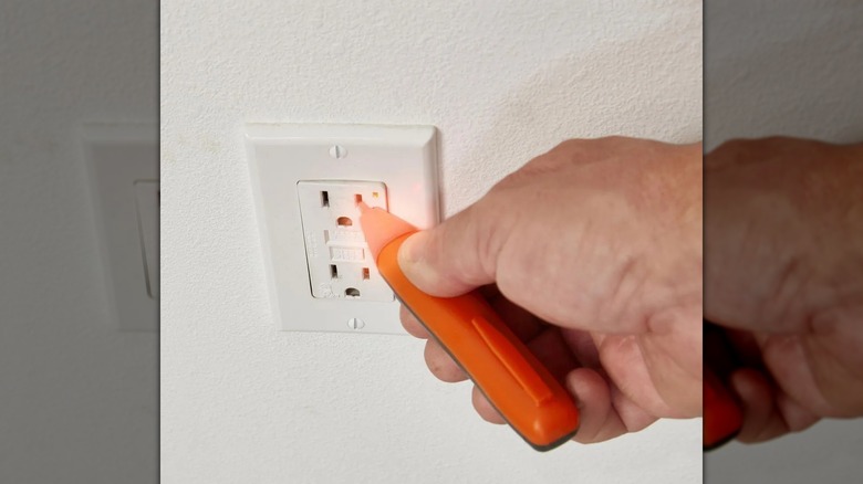 person using voltage tester on socket