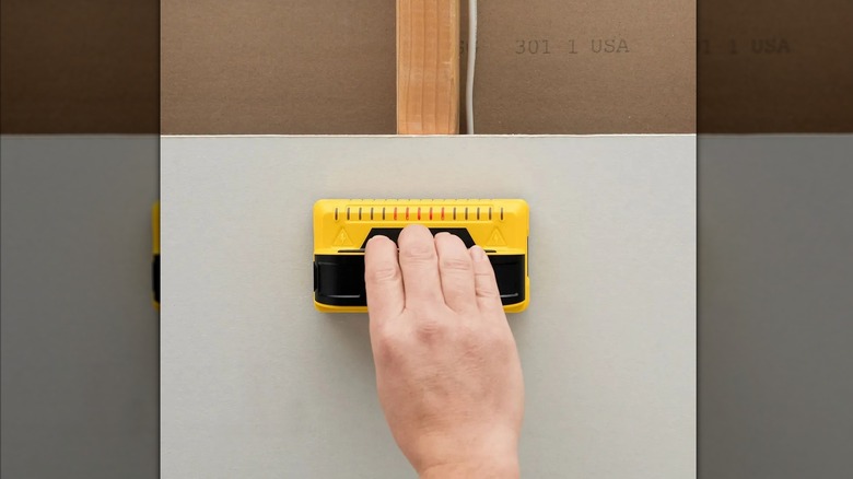 person using sensor to find stud