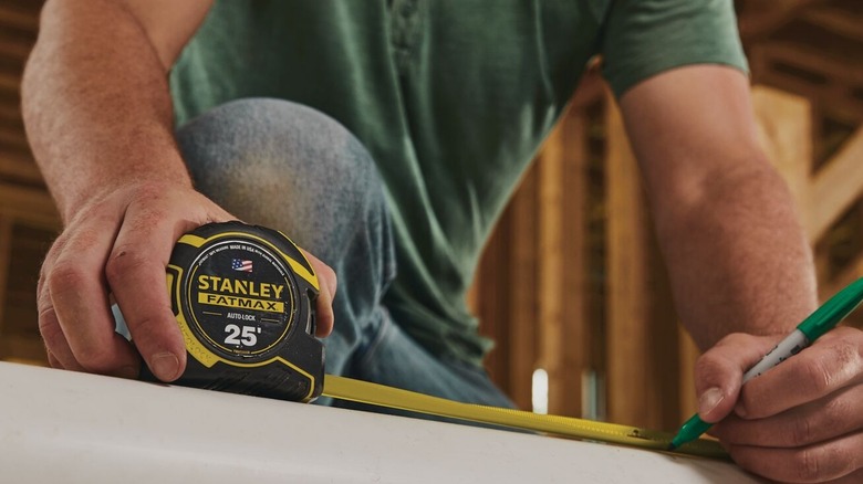Using a Stanley Fat Max 25-foot measuring tape on a construction site.