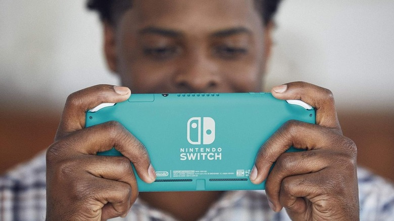 man holding turquoise Nintendo Switch Lite