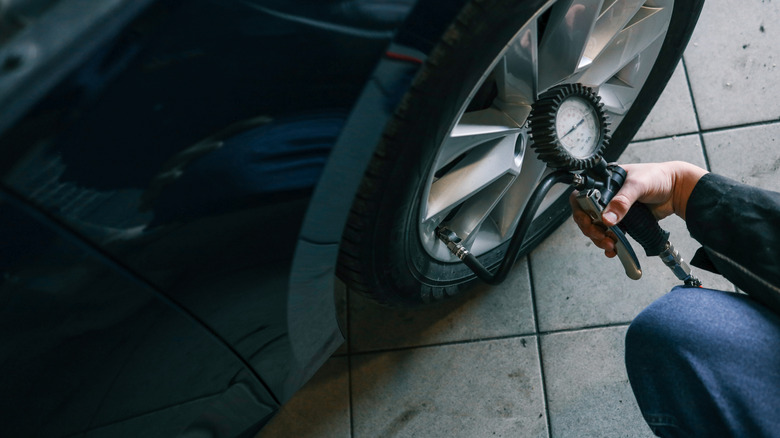 a person is checking the air pressure of his car tires with a gauge