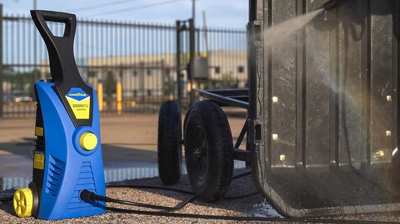 A Goodyear pressure washer outside next to a cart that's being sprayed down.