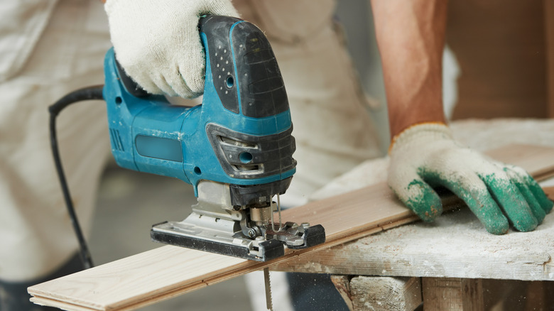 A man cutting through a wooden board with a jigsaw.