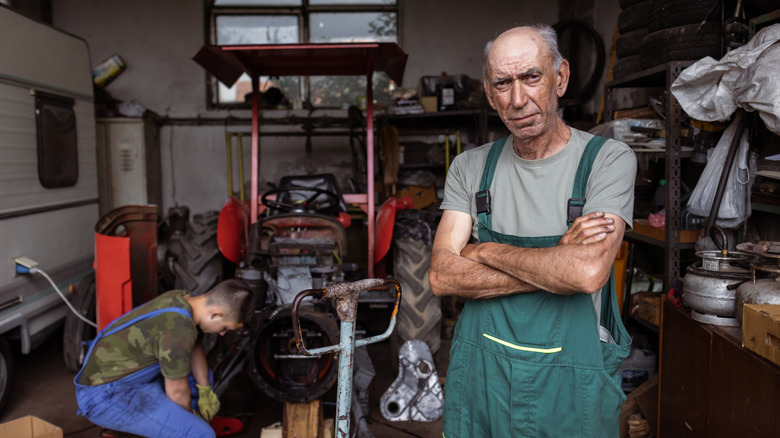 Grandfather stands by as grandchild works on car