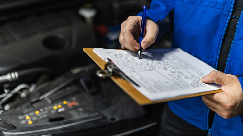 Mechanic checking off items on a car's inspection list