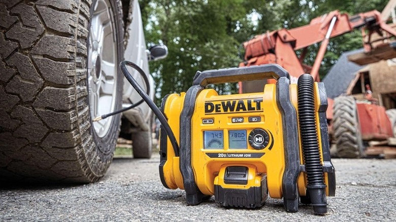 A DeWalt tire inflator on the ground, pumping air in a tire