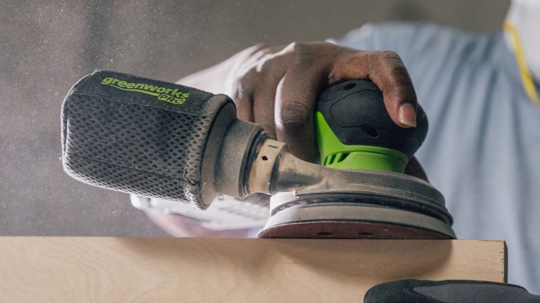 A person using a Greenworks Pro random orbit sander.