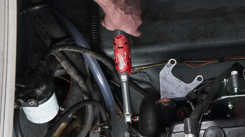 A person using a Milwaukee ratchet on a car.