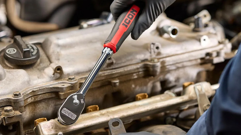 A person using an Icon ratchet on a car engine.