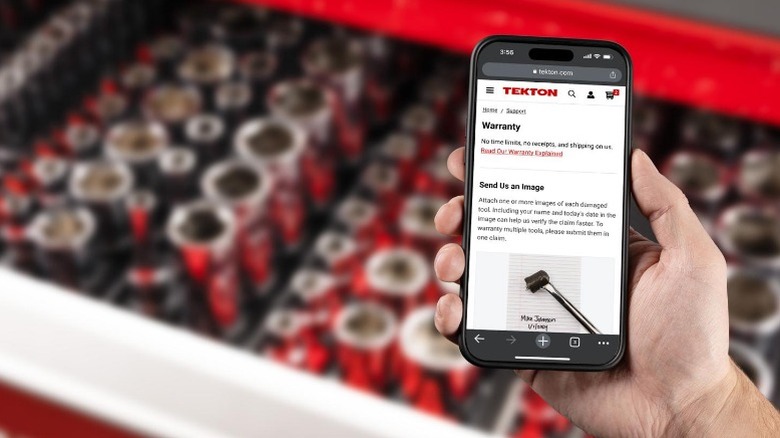 Hand holding smartphone showing Tekton's warranty page with a tool chest in the background