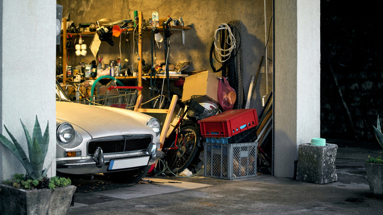 A classic car parked in a cluttered garage